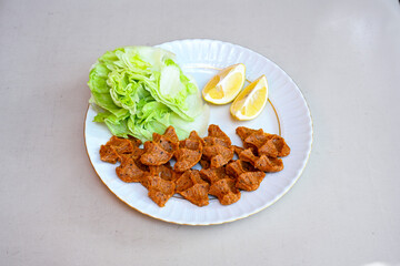 Cig kofte (raw meatball) with lettuce, tomato, pickle and lemon, hot Chee kofta. Turkish local raw food concept.Table scene of assorted take out or delivery foods. Doritoslu duble cig kofte durum.