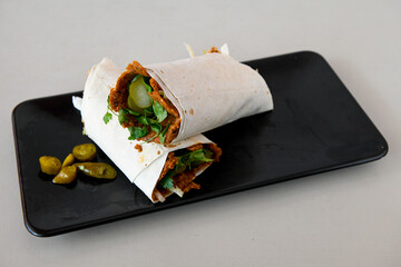 Cig kofte (raw meatball) with lettuce, tomato, pickle and lemon, hot Chee kofta. Turkish local raw food concept.Table scene of assorted take out or delivery foods. Doritoslu duble cig kofte durum.