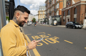 Stylish man using smartphone at london bus stop