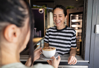Smiling barista serving cappuccino to customer in london coffee shop © PintoArt