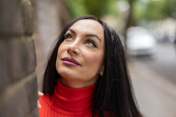 Fototapeta premium Brunette woman wearing red looking up in london street