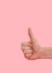 Vertical close up of Hand showing thumbs up with condom on pink background, safe sex and...