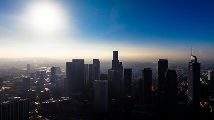 Fototapeta premium Cityscape of Los Angeles covered with thick mist. Los Angeles downtown at sunset time. Soft light dazzling the misty panorama of metropolis