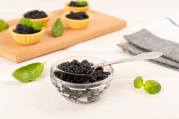 Bowl with black caviar on on wooden table
