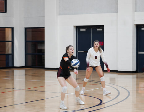 Volleyball libero passing the ball while her teammate watches