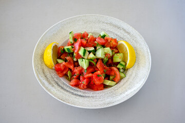 Green salad with arugula, lamb and tomatoes. Healthy vegan dish. Top view at table. Turkish Coban (choban) salata or Shepherds salad, Akdeniz salad in white bowl.