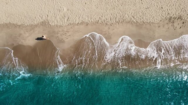 Woman in bikini walking alone beach. Sandy beach and clear turquoise waters in Mediterranean Sea. Aerial top down
