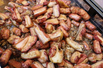 Grilled traditional sausage and different tipe of meat prepared on grill at a Christmas market where various traditional dishes are served.
