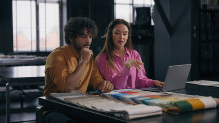 Arabian man Caucasian woman colleagues female fashion designer male tailor stylist discuss fabric cloth samples in atelier multiracial girl guy buyers customers choosing textile online shopping laptop