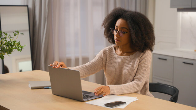 African american woman young millennial girl freelancer distant work from home quarantine female businesswoman in glasses working with laptop computer pc networking browsing online website in kitchen