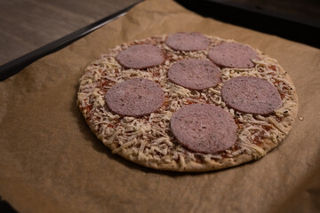 A pizza with salami and cheese on a brown paper
