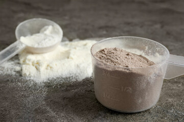 Protein powders and scoops on grey textured table, closeup
