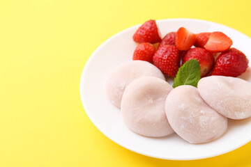 Delicious mochi and strawberries on yellow background, closeup