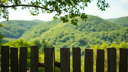 Rustic wooden fence overlooking a serene landscape of rolling green hills and lush vegetation under a bright sky