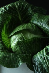 Fototapeta premium Whole ripe head of cabbage in crate on dark background, closeup