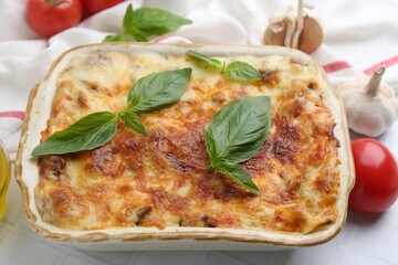 Delicious cooked lasagna with basil served on white table, closeup