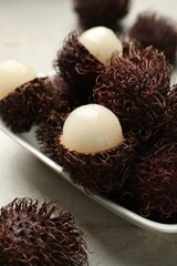 Delicious ripe rambutans on light grey table, closeup