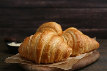Tasty fresh croissants on wooden table, closeup