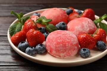 Delicious mochi, strawberries, blueberries and mint on wooden table, closeup