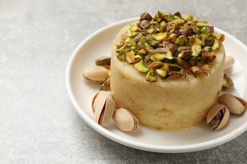 Delicious sweet semolina halva with pistachios on light grey table, closeup