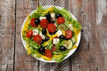 Delicious fresh Greek salad on wooden table, top view
