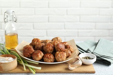 Many delicious meatballs, green onion, garlic, oil and spices on light textured table