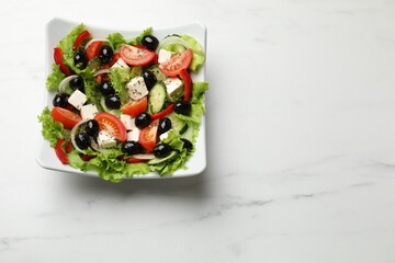 Delicious fresh Greek salad on white marble table, top view. Space for text