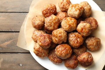 Many delicious meatballs on wooden table, top view