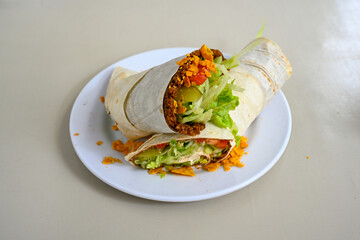 Cig kofte (raw meatball) with lettuce, tomato, pickle and lemon, hot Chee kofta. Turkish local raw food concept.Table scene of assorted take out or delivery foods. Doritoslu duble cig kofte durum.