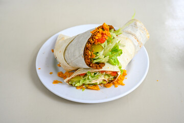 Cig kofte (raw meatball) with lettuce, tomato, pickle and lemon, hot Chee kofta. Turkish local raw food concept.Table scene of assorted take out or delivery foods. Doritoslu duble cig kofte durum.
