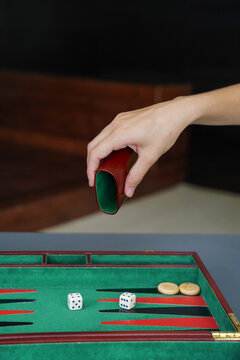 Hand Rolling Dice on Backgammon Board Represents Strategy and Luck