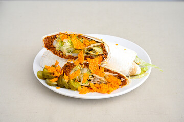 Cig kofte (raw meatball) with lettuce, tomato, pickle and lemon, hot Chee kofta. Turkish local raw food concept.Table scene of assorted take out or delivery foods. Doritoslu duble cig kofte durum.
