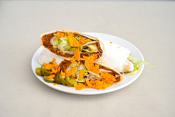 Cig kofte (raw meatball) with lettuce, tomato, pickle and lemon, hot Chee kofta. Turkish local raw food concept.Table scene of assorted take out or delivery foods. Doritoslu duble cig kofte durum.