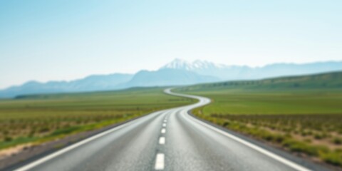 Fototapeta premium Asphalt Road Winding Through a Verdant Meadow Towards Majestic Mountains Under a Clear Sky