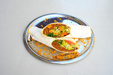 Cig kofte (raw meatball) with lettuce, tomato, pickle and lemon, hot Chee kofta. Turkish local raw food concept.Table scene of assorted take out or delivery foods. Doritoslu duble cig kofte durum.