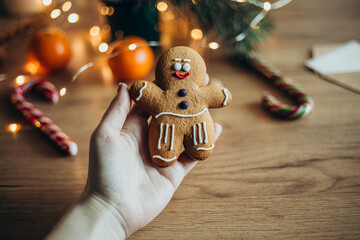Hand holding gingerbread man cookie with festive decorations