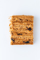 Honey cake cut with prunes and nuts inside as a textured background. Flat lay of Layered cake slice. Pastry background for confectionery shop menu on white background.