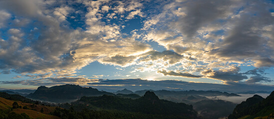 Aerial view A breathtaking view of dawn breaking over a misty mountain landscape, with layers of fog and vibrant colors painting the horizon. The serene atmosphere and natural beauty