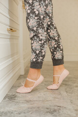 Close up of woman legs in soft pink ballet slippers on marble floor. © Olga