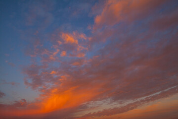 A vibrant sunset sky with dramatic clouds in shades of orange, pink, and blue.