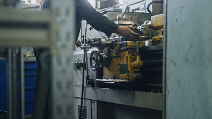 Metalworker skillfully operating a lathe machine, creating precision metal parts in a busy factory environment, highlighting the intricate techniques and craftsmanship of metalworking