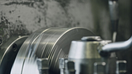 Industrial lathe machine shaping a metal cylinder in a factory setting, highlighting the intricate...