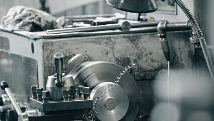 Metalworking lathe cutting a metal part, producing swarf, in an industrial workshop, showcasing the...