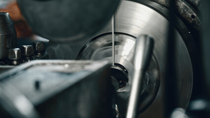 Close up view of a metal lathe cutting through a spinning metal disc, highlighting the precision and power inherent in modern industrial manufacturing techniques