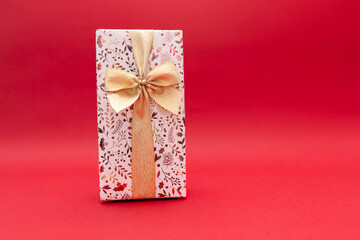 The wrapped gift should be on a bright red background with a gold ribbon, a gift for a birthday, Valentine's Day, New Year.