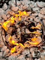 Burning fire in a round wooden bowl on a stone background outdoors in winter time