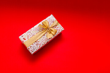 The wrapped gift box on a bright red background with a gold ribbon, a gift for a birthday,...