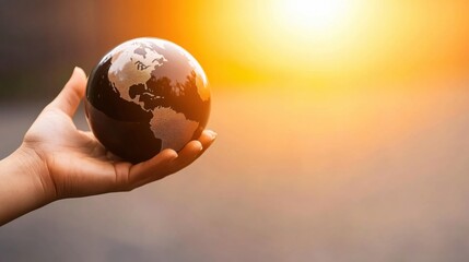Hand Holding Globe Against Sunset Background Representing Global Unity