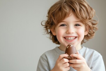 A joyful child celebrating Easter, holding a delicious chocolate egg, radiating happiness and excitement as he poses for the camera, embodying the delightful spirit of this special occasion