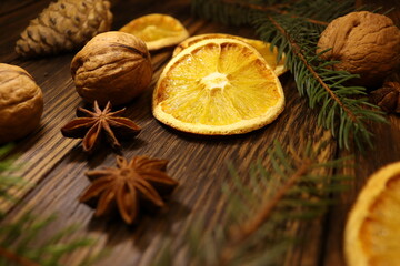 
close-up of dry leaves, spruce twig, red viburnum and star anise, nuts and oranges on a wood background